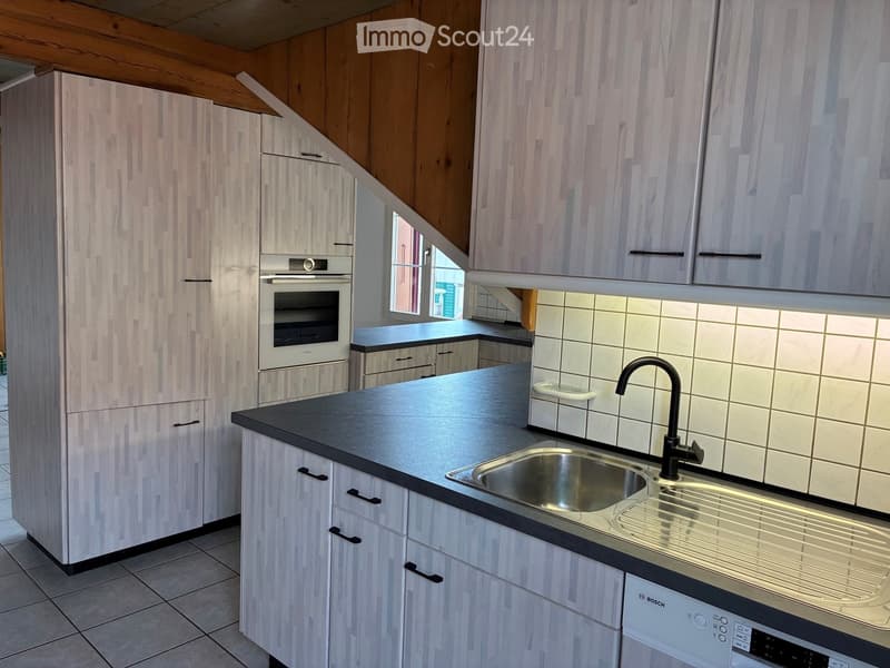Modern kitchen with light wood cabinets, stainless steel sink, and Bosch appliances.