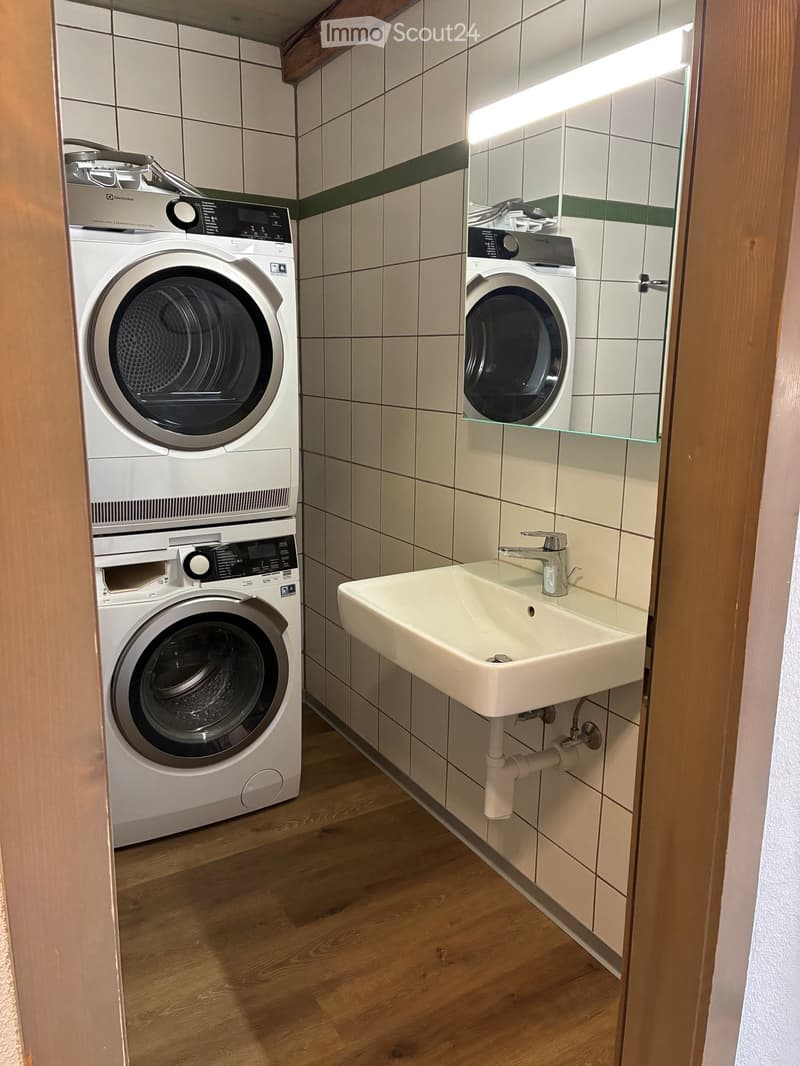 Bathroom with a sink, faucet, and stacked washing machine and dryer unit.
