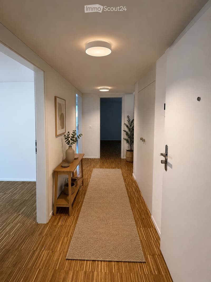 Modern hallway with wooden flooring, white walls, recessed lighting, a small wooden table with a vase and plant, a picture frame on the wall, and a beige runner rug.