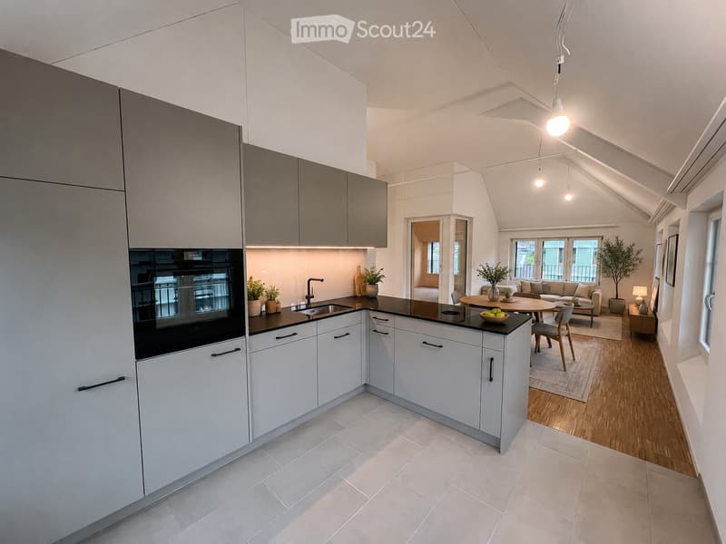 Modern kitchen with white cabinets, black countertop, and stainless steel appliances. Adjacent living area features a sofa, coffee table, and dining table with chairs.