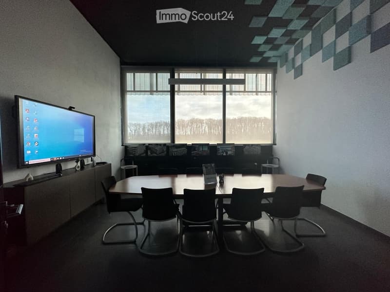 Conference room with a large table, chairs, a screen, and a cabinet with speakers.