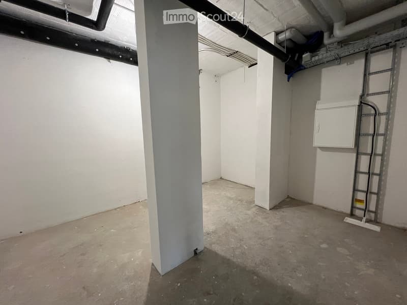 Empty room with bare walls, concrete floor, and visible structural elements including a pillar, ladder, and electrical panel.