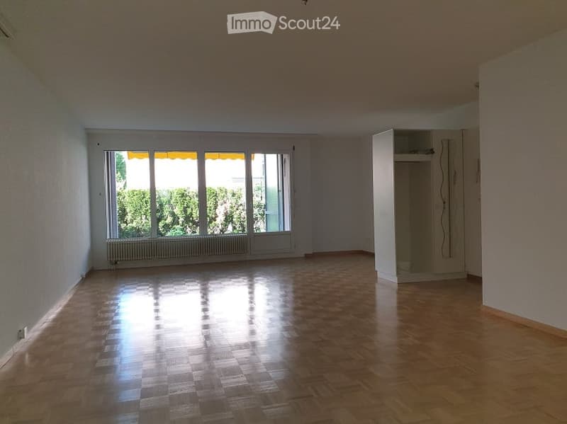 Empty room with wooden flooring, large windows, and a radiator beneath them. No furniture or equipment present.