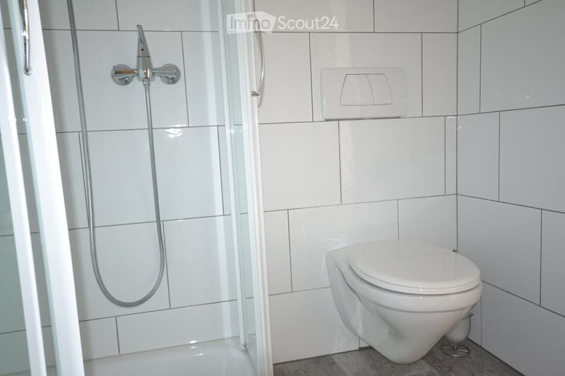 Bathroom with glass enclosed shower, white tiles, white toilet