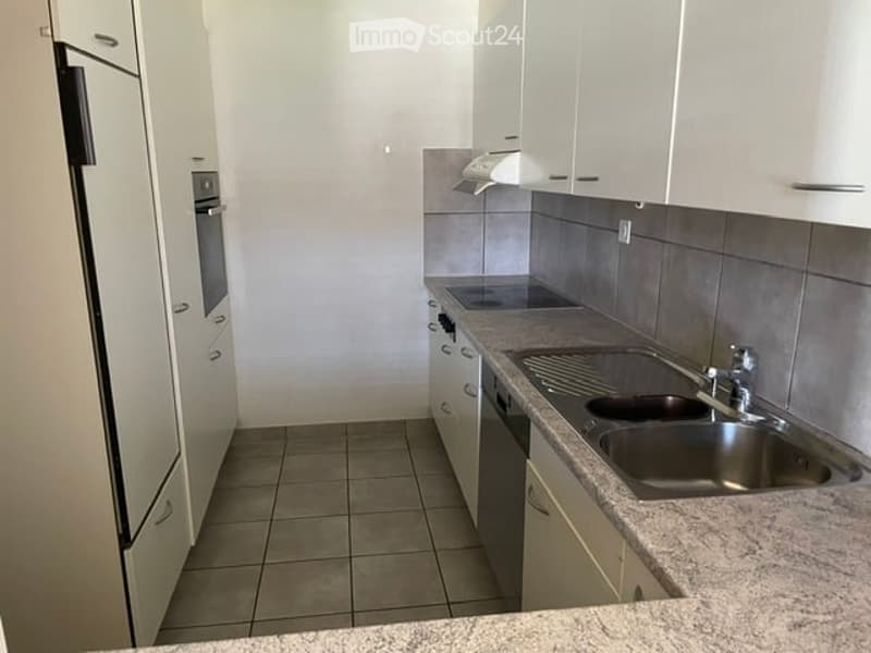 Modern kitchen with white cabinets, stainless steel appliances, granite countertop, and tiled floor.