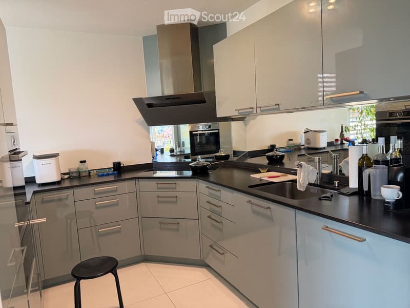 Modern kitchen with white cabinets, black countertops, stainless steel appliances, and various kitchen items on the counter.