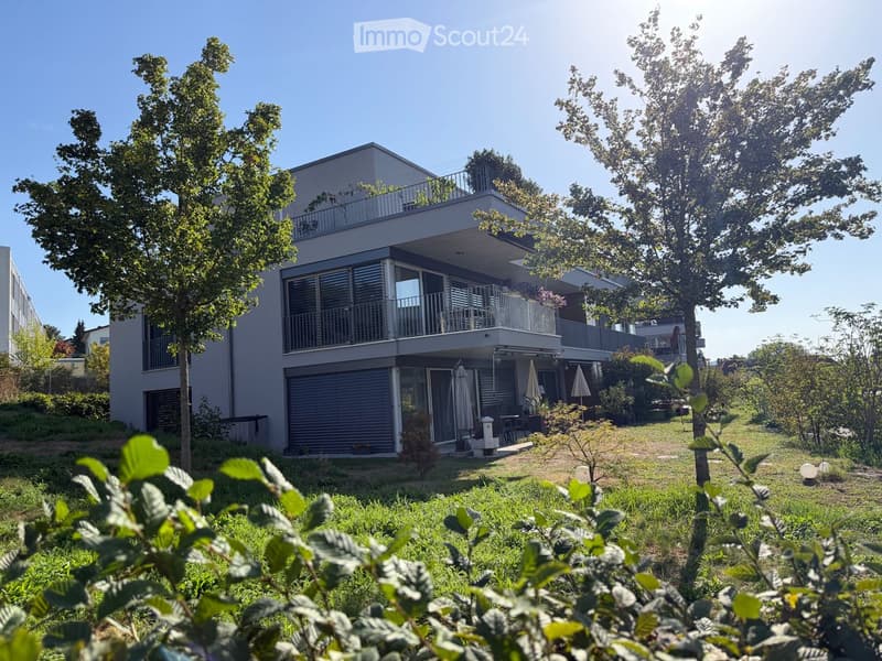 Modern two-story house with balconies, large windows, and a well-maintained garden.