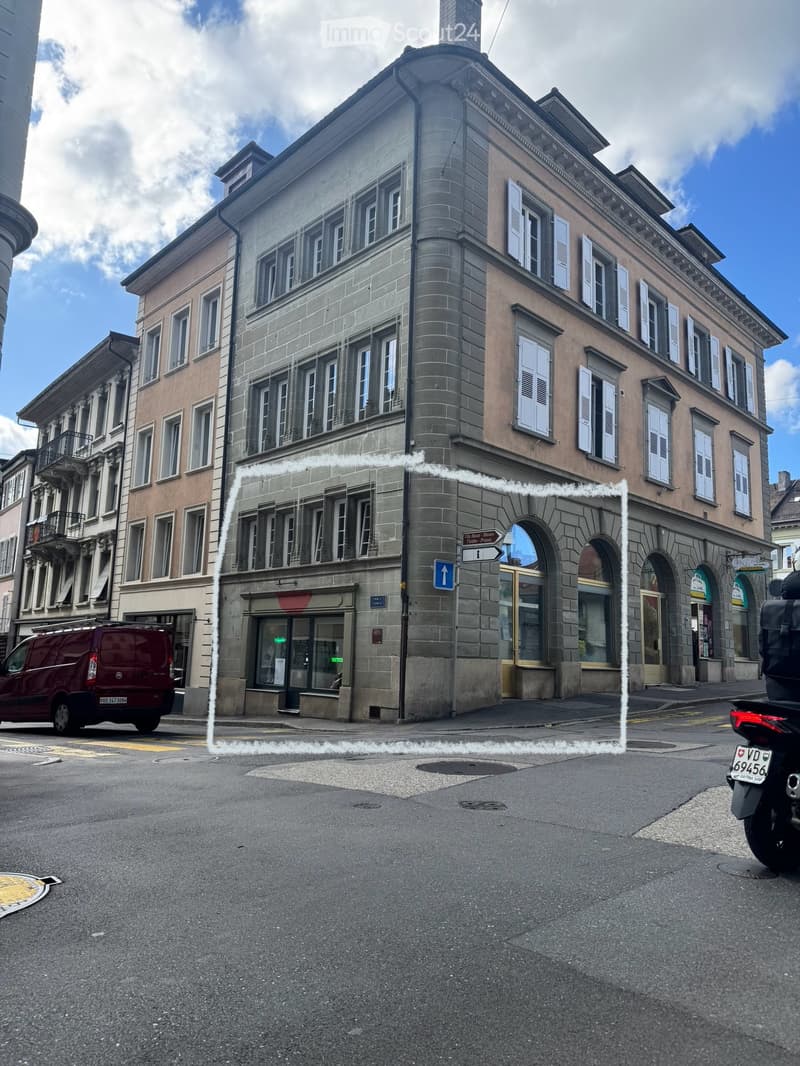 Multi-story building with classic architecture, arched entrance, and multiple windows with shutters.