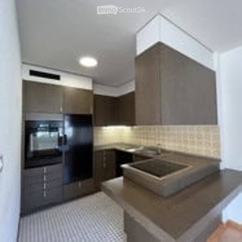 Modern kitchen with dark cabinets, stainless steel appliances, and a central island with a sink.