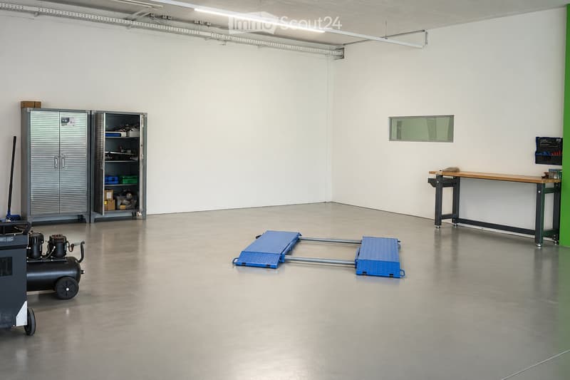 Workshop or garage space with a metal cabinet, workbench, air compressor, and work platform.