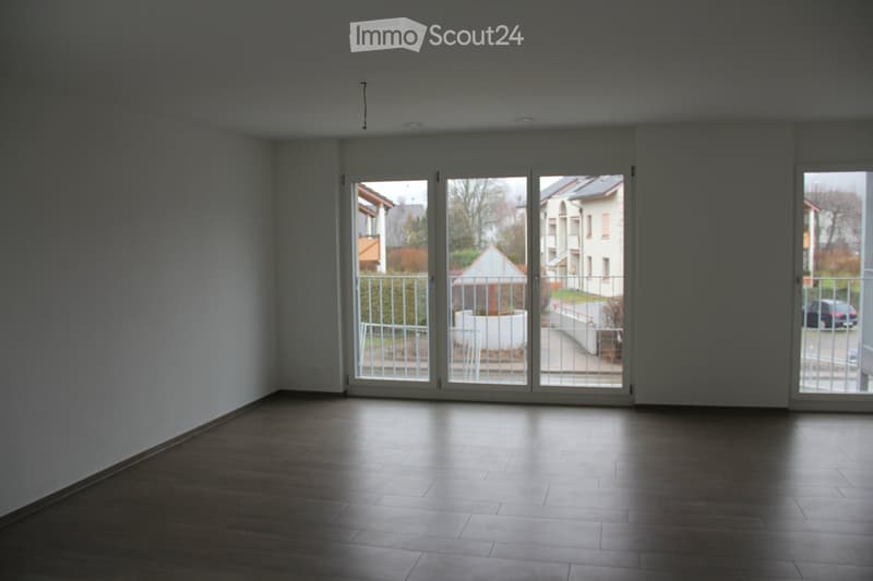 Empty room with wooden flooring and large sliding glass doors leading to a balcony area.