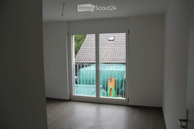 Empty room with wooden flooring, white walls, and large sliding glass doors leading to a covered outdoor area.