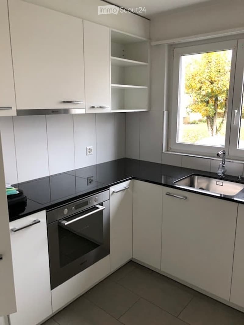 modern kitchen with white cabinets, black countertops, oven, stainless steel sink, faucet, dishwasher, and window