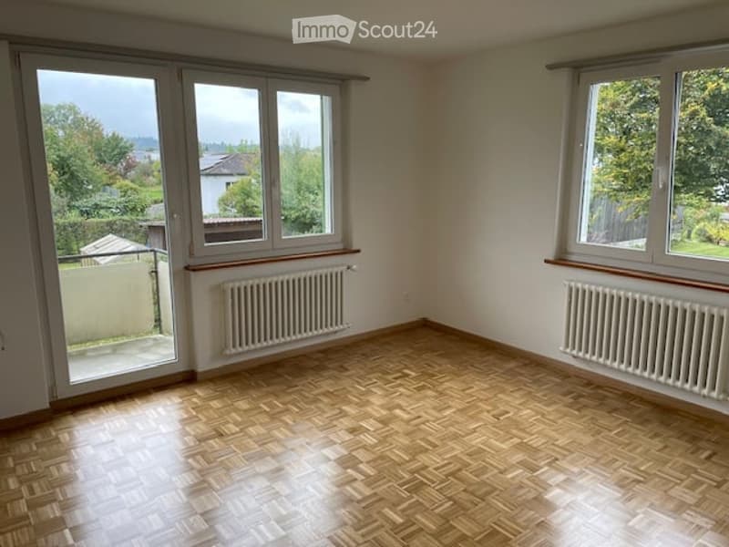 wooden floor, two large windows, two radiators, balcony, white walls