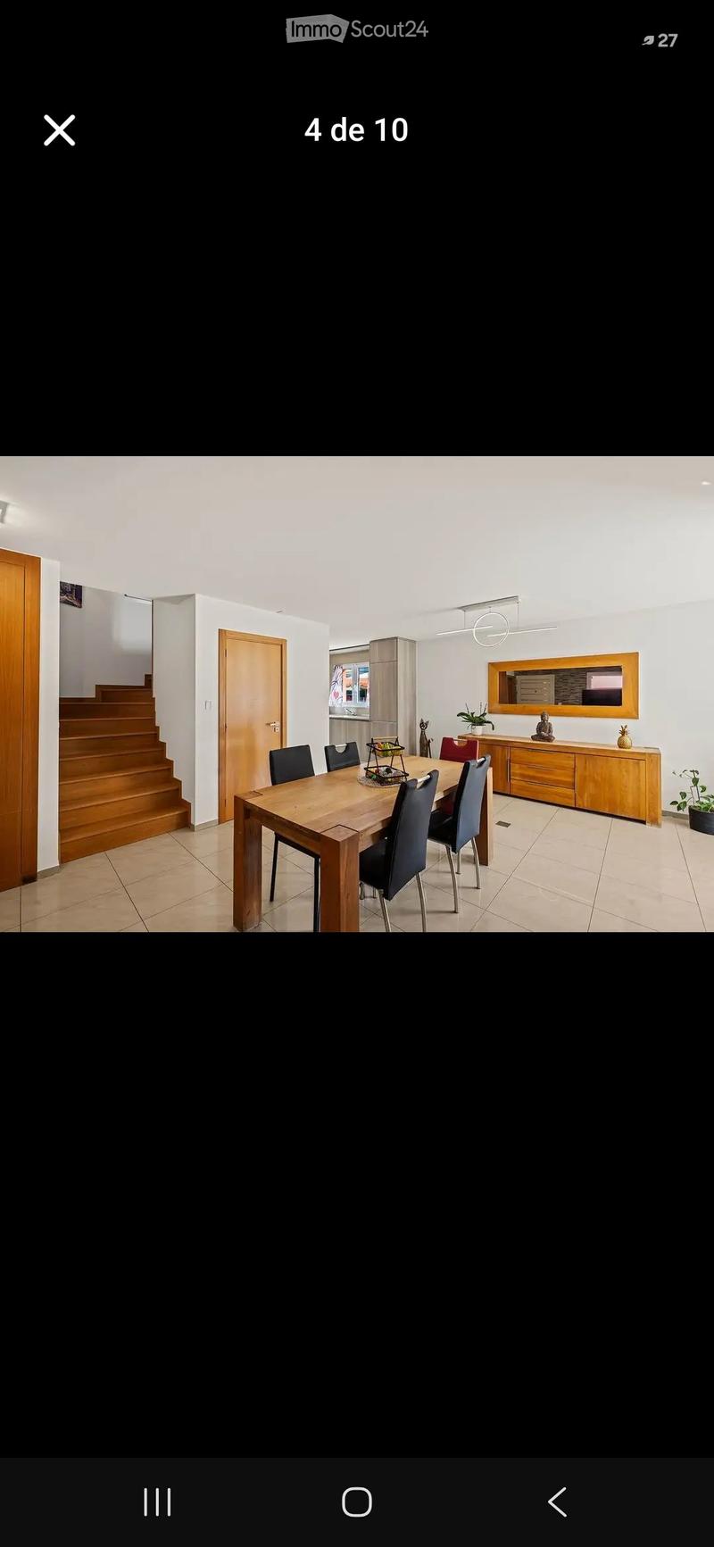 Dining room with a wooden dining table, six chairs, a wooden cabinet, a mirror, and a small plant on the floor.