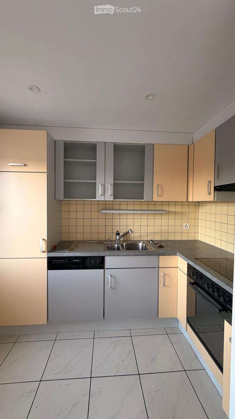 Modern kitchen with light-colored cabinets, a stainless steel sink, a dishwasher, and an oven. The floor is tiled with a marble-like pattern.
