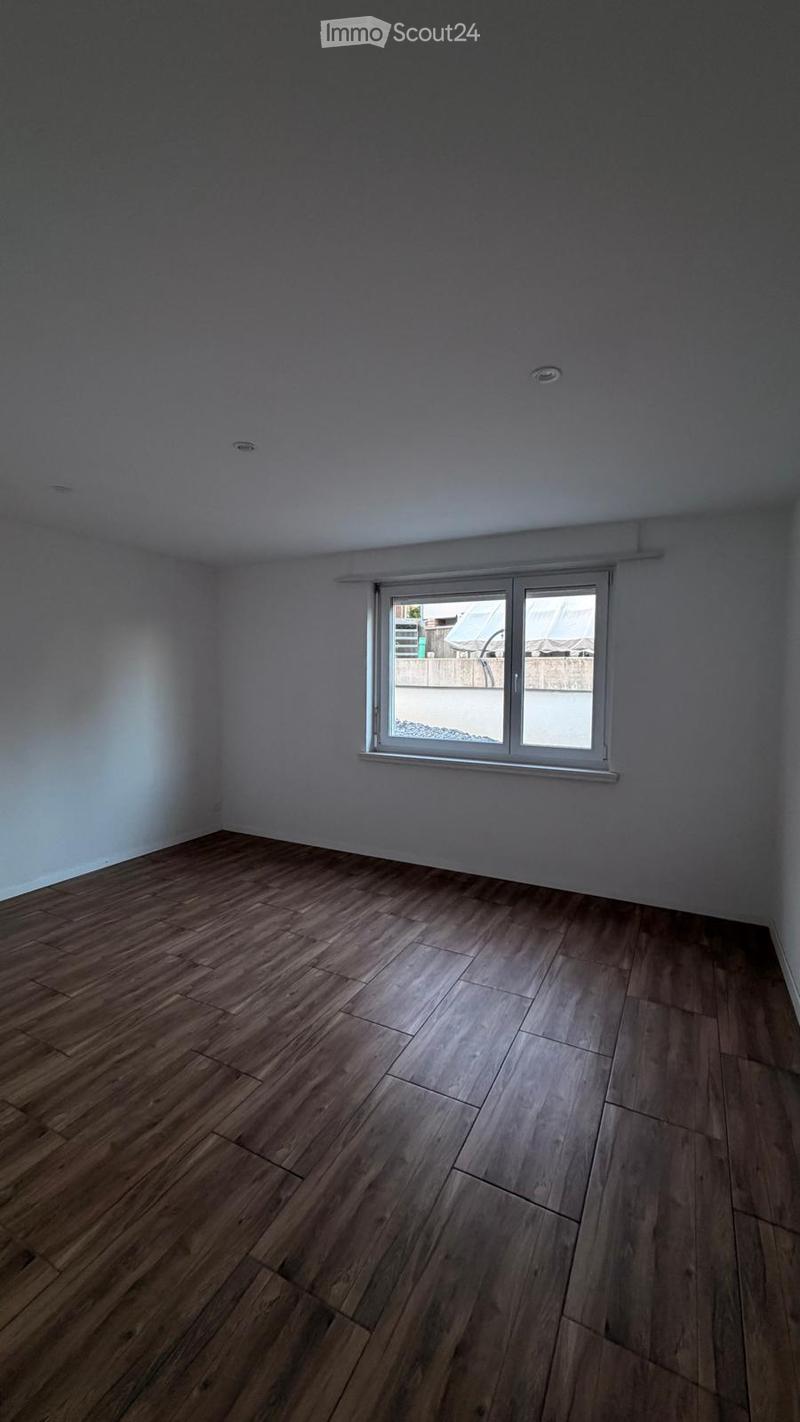 Empty room with wooden flooring and a single window, no furniture or equipment present.