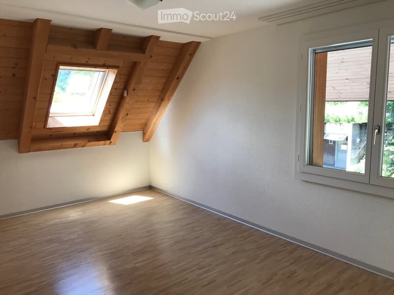 Empty room with wooden floor, white walls, large window, and skylight.