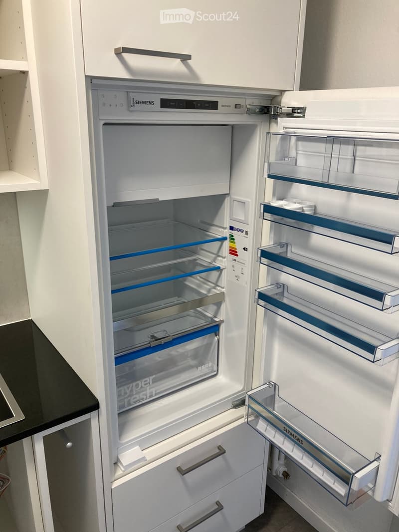 A modern kitchen featuring a white Siemens refrigerator with multiple compartments and shelves, integrated into white cabinetry.