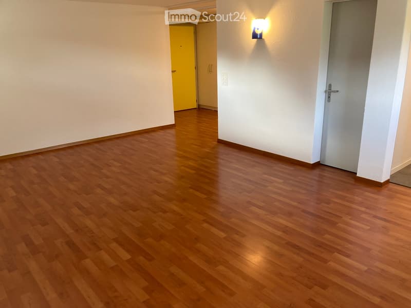 Empty hallway with wooden flooring, white walls, and two doors (one yellow, one white) on either side.