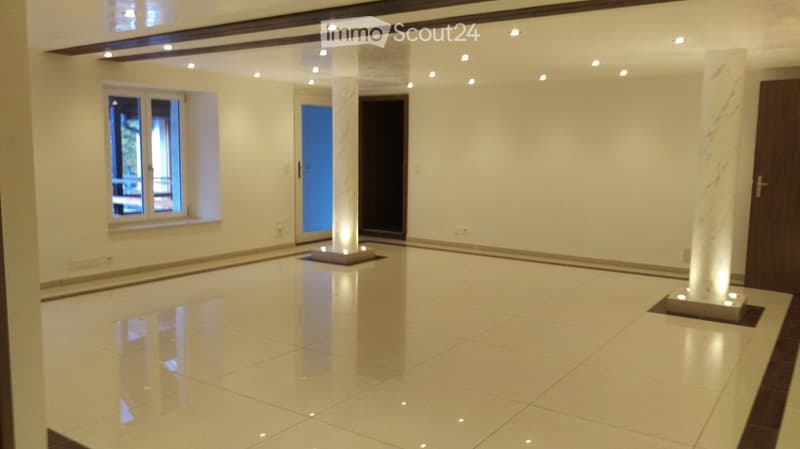 Empty room with polished tile flooring, white walls, recessed lighting, and a large window with a view of outdoor furniture.