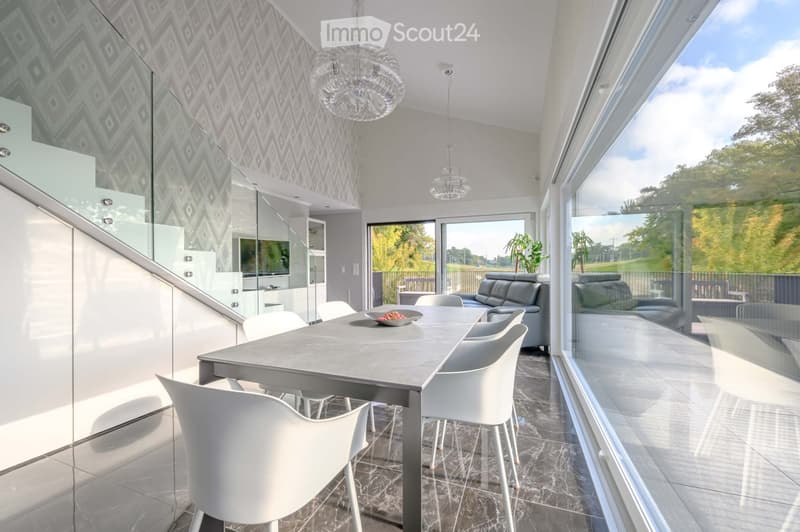 Furnished Room. Modern dining area with a large table, white chairs, and a view of the outdoors.