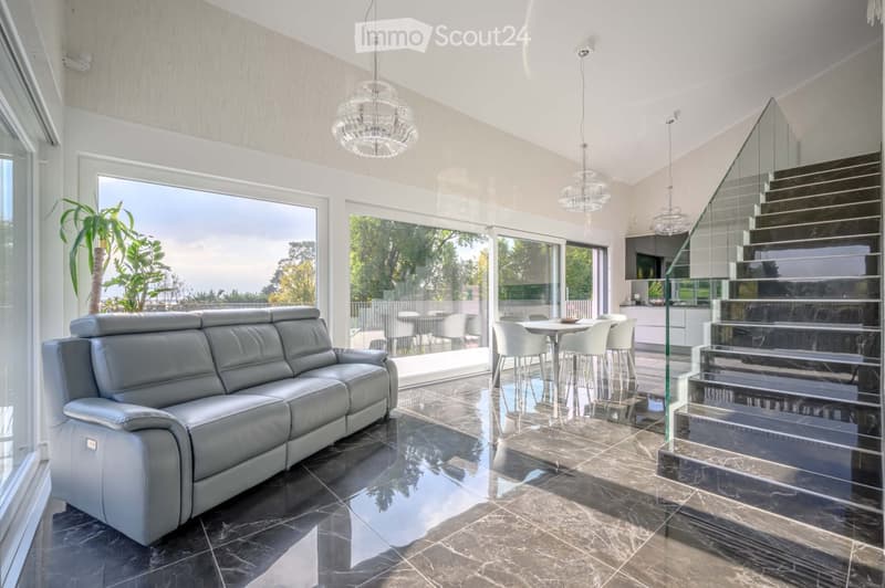 Living Room. Spacious living room with a large leather sofa, dining table, and glass walls offering a view of the outdoors.