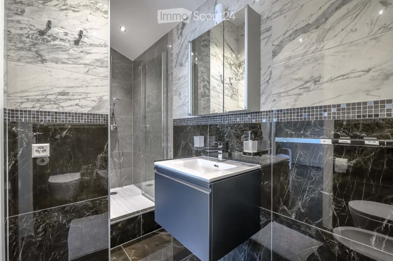 Bathroom. Modern bathroom with marble tiles, glass shower enclosure, vanity with sink, and a toilet area.