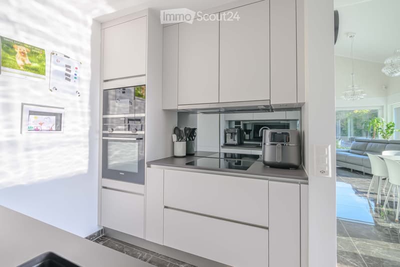 Kitchen. Modern kitchen with white cabinets, granite countertops, built-in oven and microwave, and a coffee machine on the counter.
