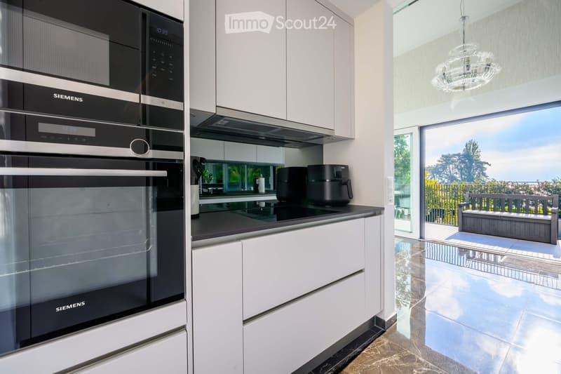 Kitchen. Modern kitchen with white cabinets, black countertops, Siemens appliances, and a view of the outdoors.