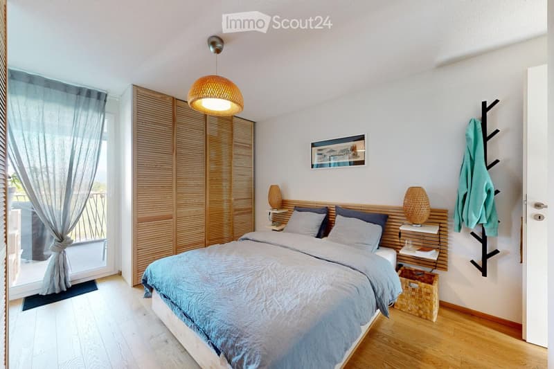 Modern bedroom with a large bed, nightstands, lamps, a picture frame on the wall, and a curtained window leading to a balcony.