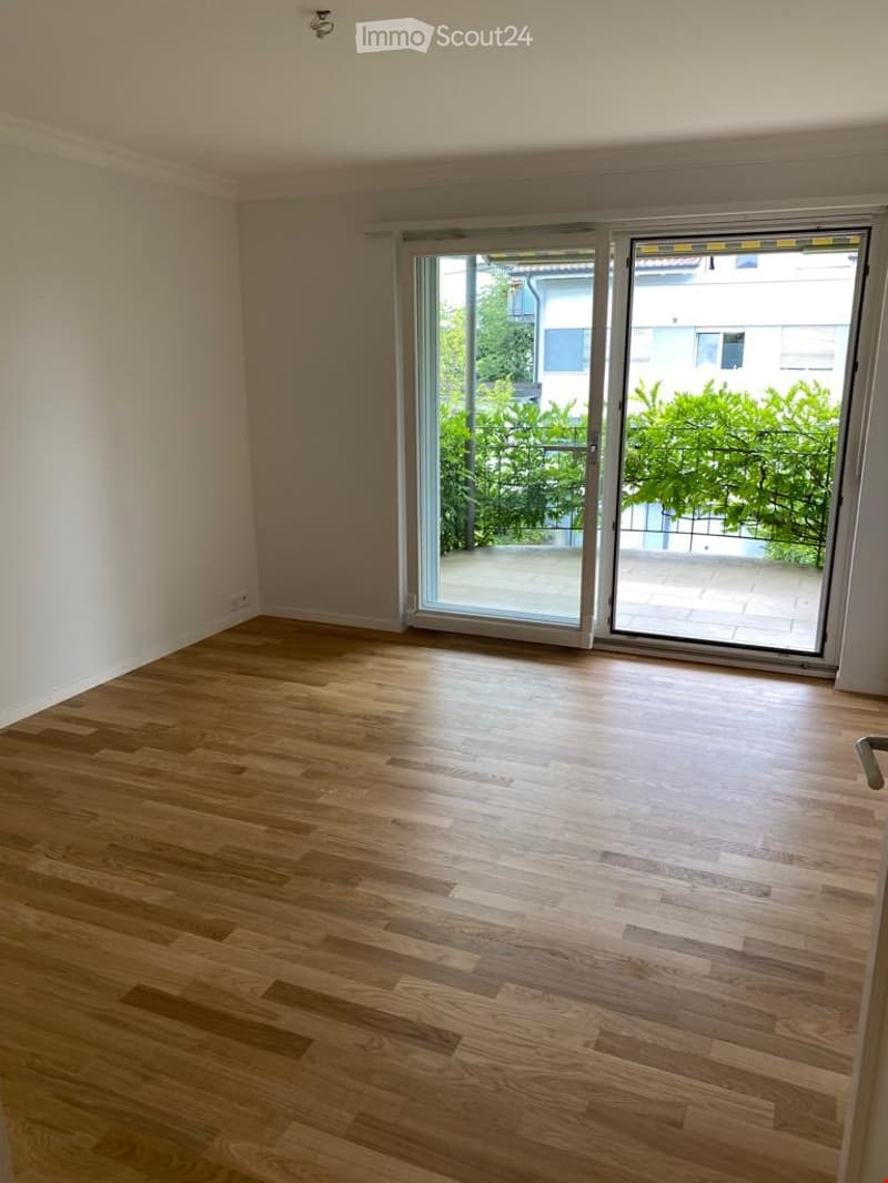 Empty room with wooden flooring and large sliding glass doors leading to a balcony area.