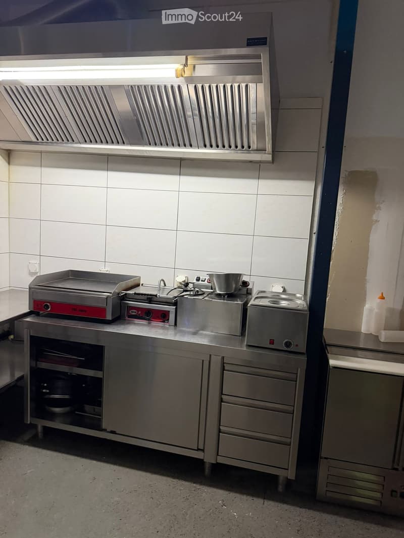 commercial kitchen with stainless steel appliances and white tiled wall