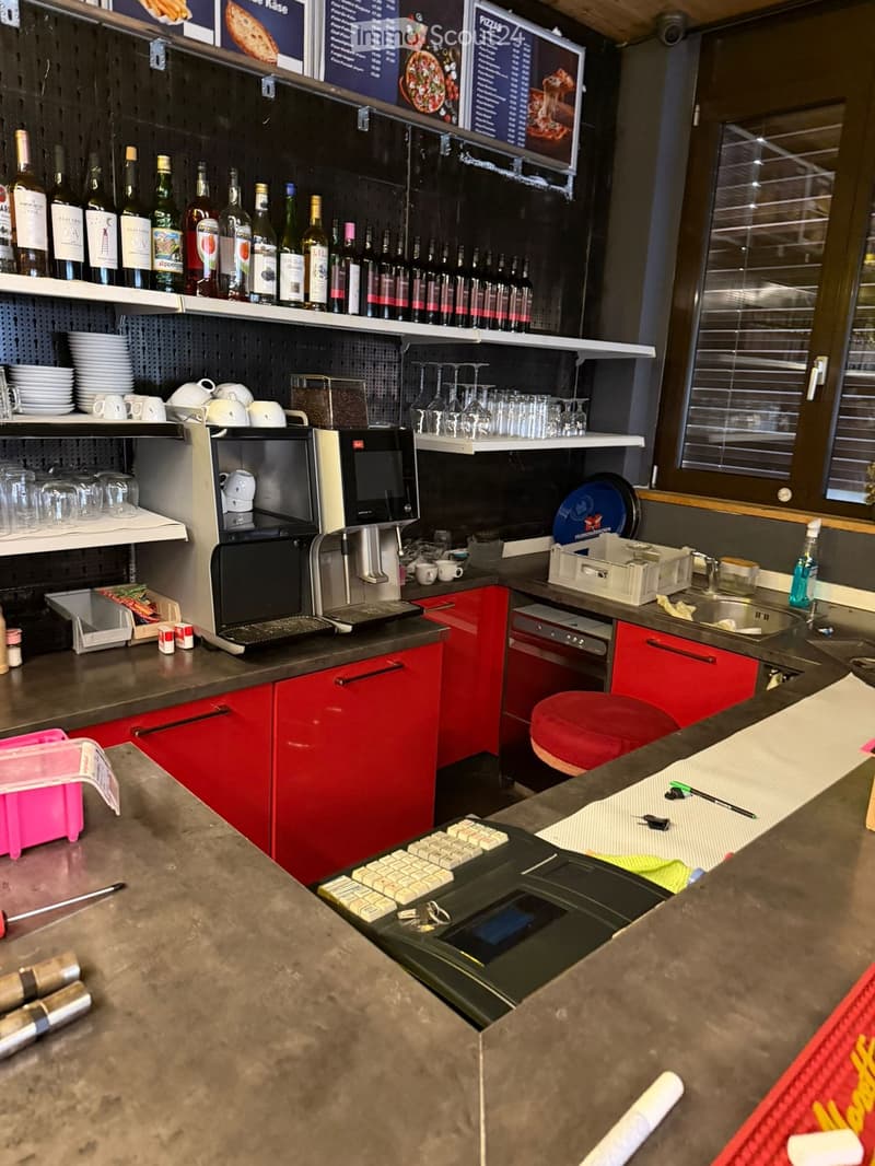 Red cupboards, tiled wall, black countertop, espresso machine, dishes, sink