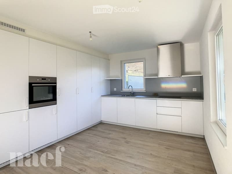 Modern kitchen with white cabinets, stainless steel appliances, and wooden flooring.