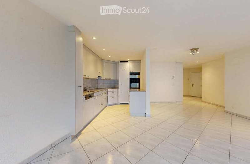 Empty kitchen with white cabinets, stainless steel appliances, and tiled flooring.