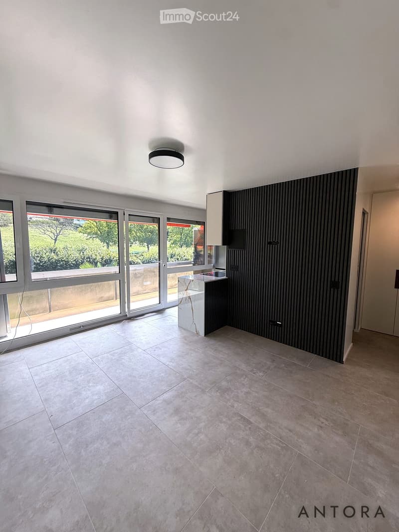 Empty room with tiled floor, large windows, and a small cabinet. No furniture or equipment present.