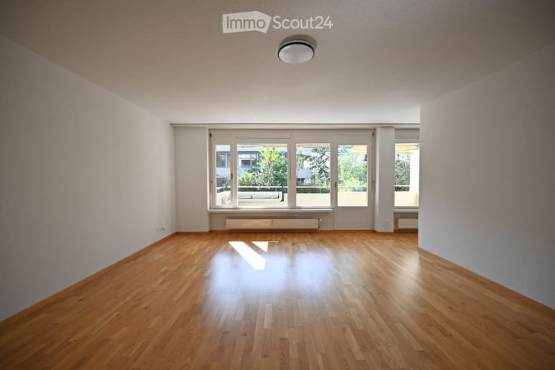 Empty room with wooden flooring, large windows, and white walls. No furniture or equipment present.