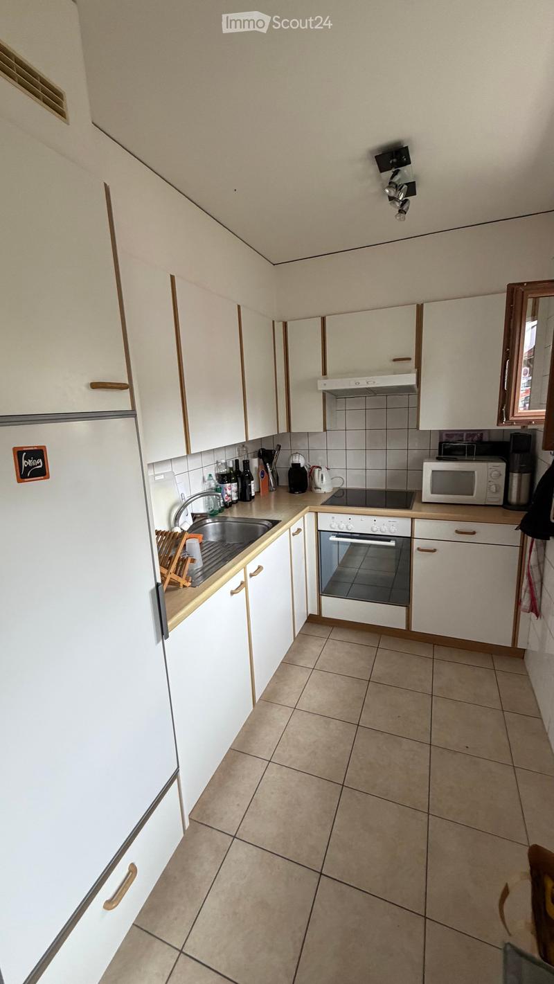Modern kitchen with white cabinets, tiled floor, and various appliances including a sink, oven, microwave, and refrigerator.