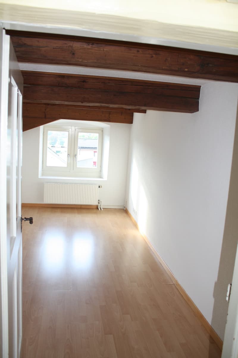 Empty room with wooden beams, wooden floor, white walls, window with white frames