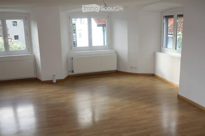 empty room, wooden floor, white walls, three windows, radiators, electrical outlets