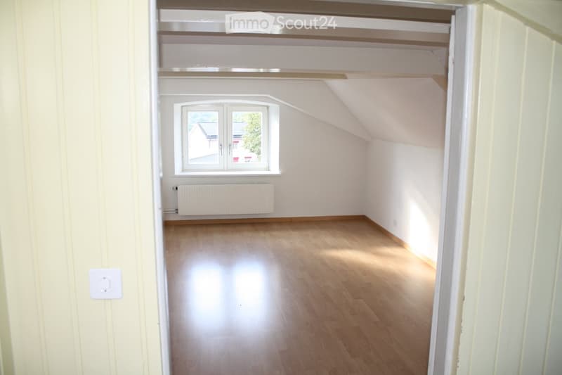 empty room with wooden floors, white walls, sloped ceiling, and window
