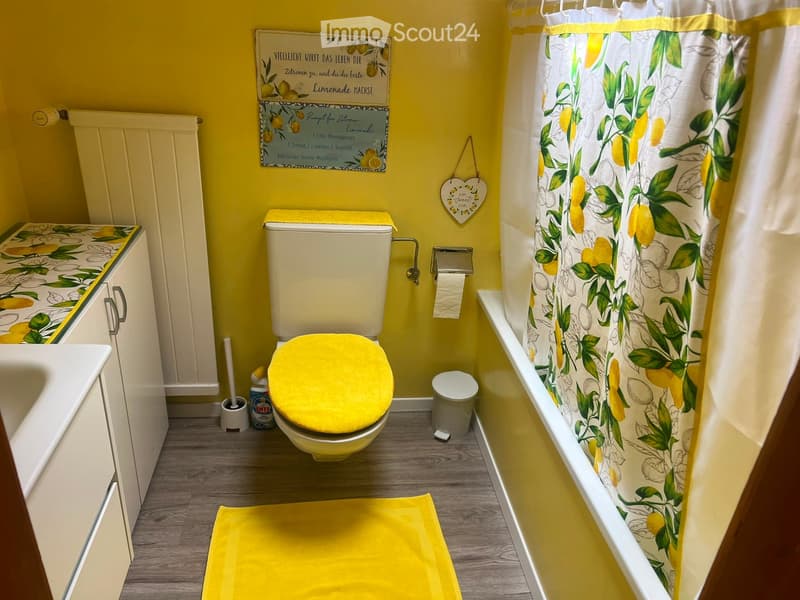 Bright yellow bathroom with a lemon-themed design, featuring a toilet, sink, bathtub, and matching shower curtain.