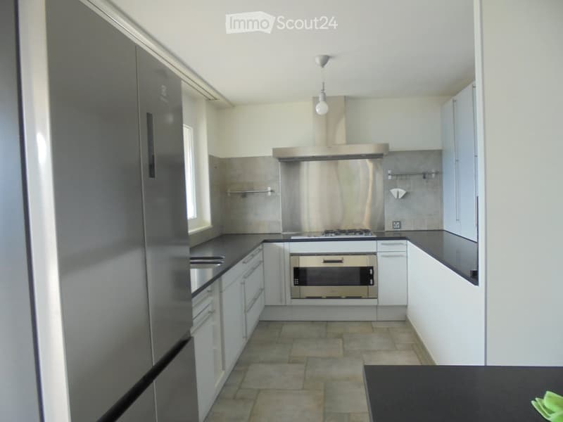 Modern kitchen with stainless steel appliances, white cabinets, and a black countertop.