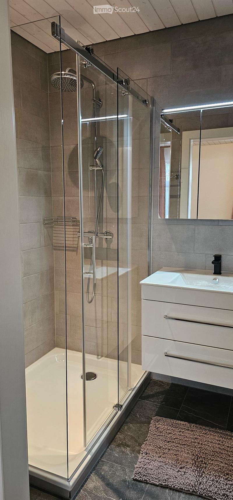 modern bathroom with glass shower enclosure, white sink, mirror, and tiled floor