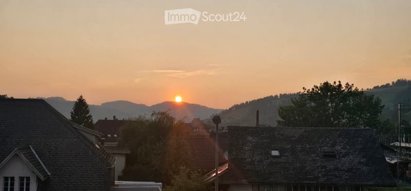 Sunset over a town with mountains in the background
