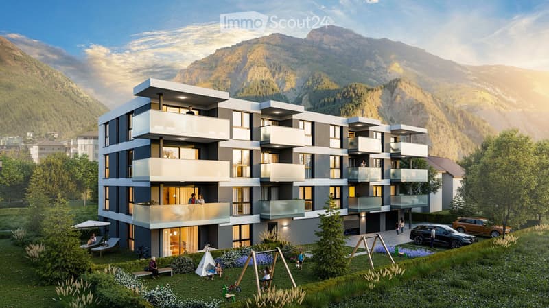 Modern multi-story residential building with balconies, surrounded by a landscaped garden area with swings, a teepee, and parked cars.
