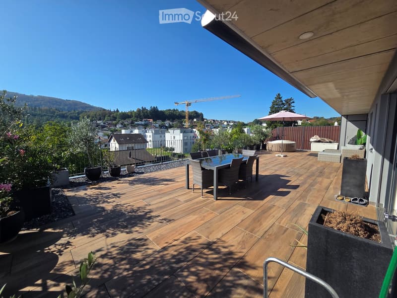 Wooden deck terrace with a dining set, umbrella, hot tub, and scenic mountain view.