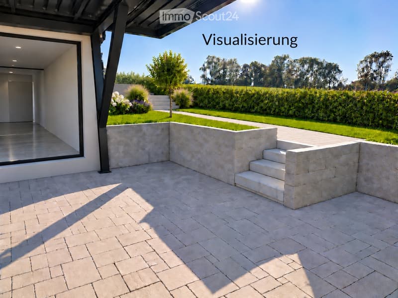 Modern outdoor patio with light-colored stone tiles, low stone walls, steps leading to a grassy area, and a view of a landscaped garden with trees and shrubs.