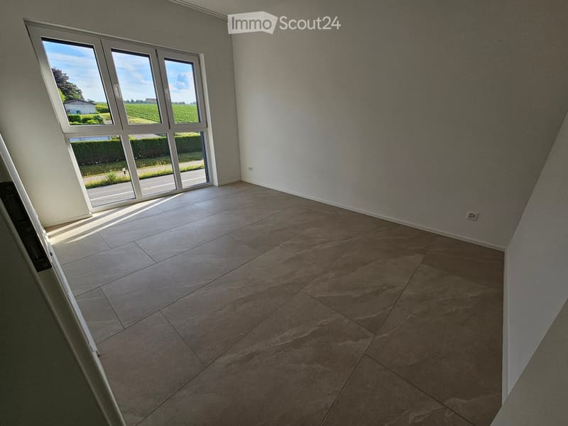 Empty room with tiled floor and large windows offering a view of the countryside.